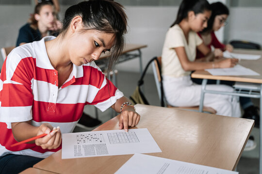 Female Student writing exam exercise in the college high school classroom. Secondary education.