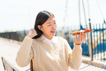 Young Chinese woman holding sashimi at outdoors celebrating a victory