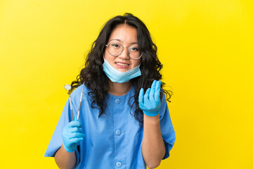 Young asian dentist holding tools over isolated background making money gesture