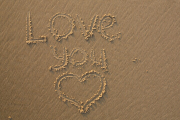 The tekst Love You written in the sand and a heart drawn next to it
 - obrazy, fototapety, plakaty
