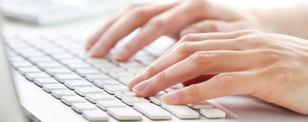 Woman's hands typing on white keyboard, sunlight highlighting gentle motion and productivity