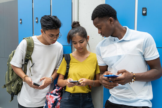 Generation Z teenagers addicted to internet and social media on their mobile phones on school campus.