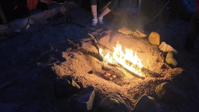 Friends playing live music, having fun at the bonfire on the beach at night, 4K