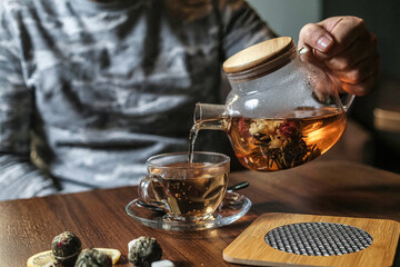Person Pouring Tea Into Glass Cup