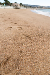 Footsteps on a sand beach of South France during spring with sea waves