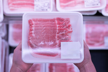 パックに入った豚肉を持った子供の手