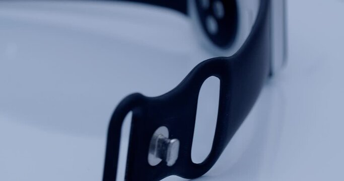 smart watch with a strap that rotates around its own axis, illuminated by white studio light