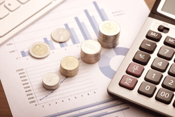 Financial concepts - coins and calculators placed on financial data reports