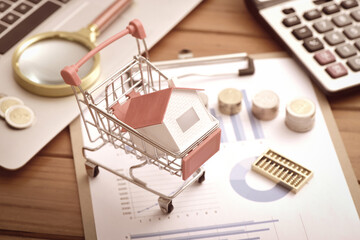 Laptops, coins, abacus, and small houses placed in shopping carts on data drawings