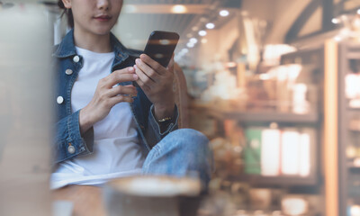 Young asian woman using mobile phone during online working at coffee shop. Casual business woman using smartphone connecting the internet, telework at cafe