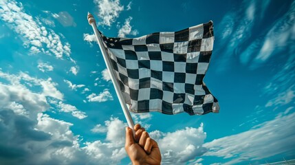 Hand waving a checkered race flag under blue skies.