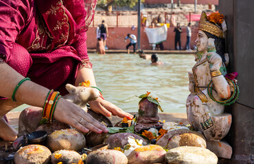 devotee praying for holy god shivalinga with flowers at river shore at morning