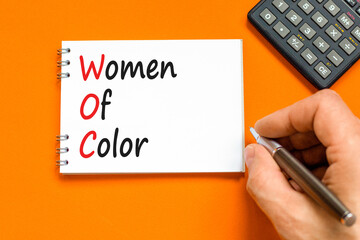 WOC women of color symbol. Concept words WOC women of color on beautiful white note. Beautiful orange background. Businessman hand. Business WOC women of color social issues concept. Copy space. - obrazy, fototapety, plakaty