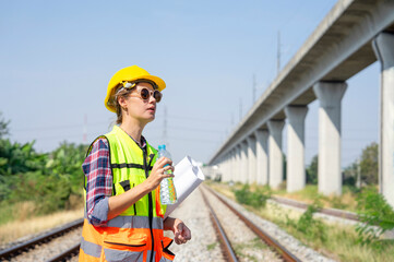 railway engineer or construction worker in hardhat and safety vest,holding paperwork is thirsty in...
