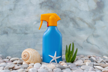 SPF. A bottle of sunscreen on the pebbly seashore is decorated with seashells. Sun lotion. UVA UVB....