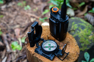 Old compass with handy talkie on a log, in the forest. direction finder compass. concept of hunting...