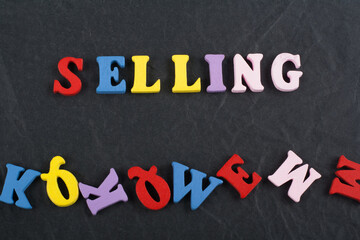 SELLING word on black board background composed from colorful abc alphabet block wooden letters, copy space for ad text. Learning english concept.