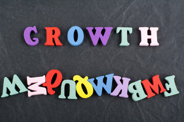 Growth word on black board background composed from colorful abc alphabet block wooden letters, copy space for ad text. Learning english concept.