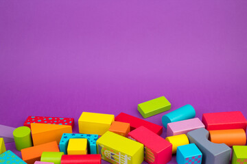 Top view of colorful wooden bricks on the table. Early learning. Educational toys on a purple background.