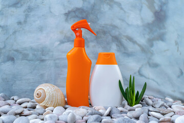 SPF. A bottle of sunscreen on the pebbly seashore is decorated with seashells. Sun lotion. UVA UVB....