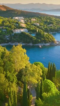 Gorgeous mediterranean landscape of Corfu island, Greece. Flying over lush green vegetation, villas and sea bays on Corfu island. Tourism landmark honeymoon travel destination. Vertical Screen