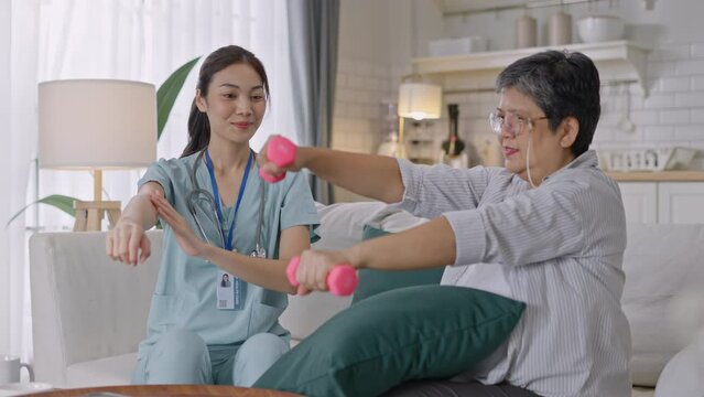 Asian Elderly woman holding a dambell used for rehabilitation in home,doing arm and hand physiotherapy for elderly woman, to Physical therapy,treat myasthenia gravis,to nursing home concept