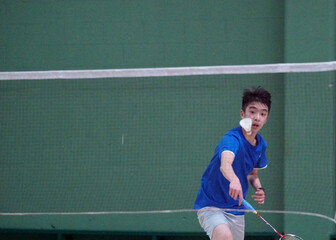 A teen boy plays a badminton tournament