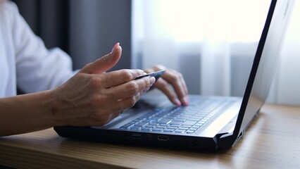 Woman makes online purchases seamlessly using her bank card. Shopping cart fills with items as bank...