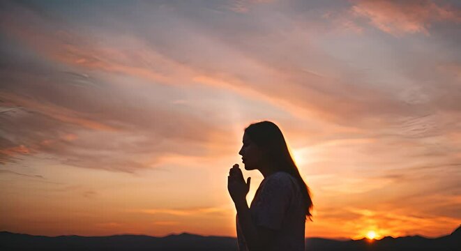 Woman praying at sunset.
