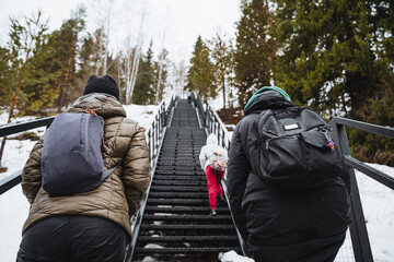 Two individuals climbing snowy stairs, braving freezing weather - obrazy, fototapety, plakaty