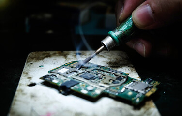 Mobile phone repairman who is dismantling and repairing the equipment inside the telephone.