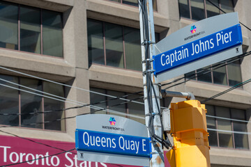 Fototapeta premium city of Toronto street signs at Queens Quay East and Captain John (Waterfront BIA)