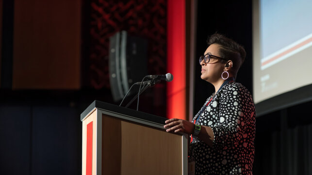 Keynote lecture by a non-binary professional speaker at a corporate event on inclusive diversity and lgbtq empowerment. Addressing a diverse audience in a modern business seminar workshop