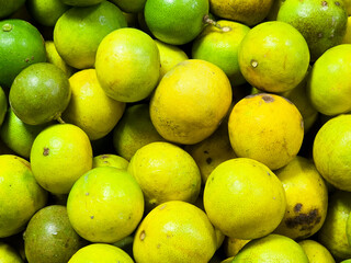 Piles of medium-sized yellow-green lemons with both beautiful and unattractive skins in the vegetable shop