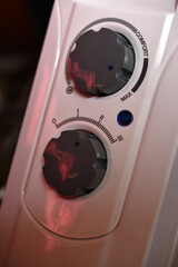 Round switches on a white radiator. The control panel.