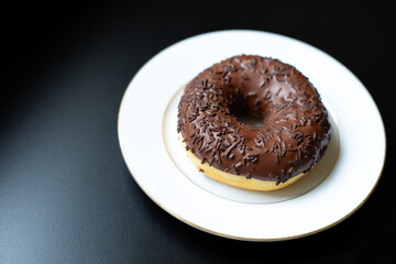Baked round donut with chocolate on a dark background