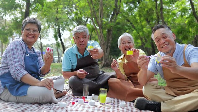 Art activities for the elderly. A group of elderly people sit and paint pots in the garden outside. They are happy. Living happily in retirement. art therapy. Elderly community