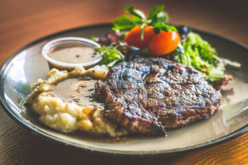 Ribeye steak with.Mashed potato and gravy, mesclun salad and mushroom sauce.