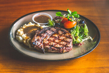 Ribeye steak with.Mashed potato and gravy, mesclun salad and mushroom sauce.