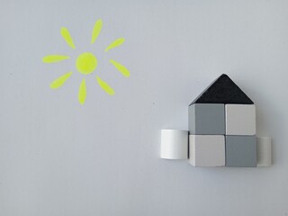 house made of wooden gray cubes with sun on a white background