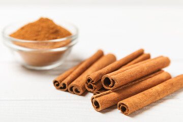Cinnamon sticks on a textured wooden background. Cinnamon roll. Spicy spice for baking, desserts and drinks. Fragrant ground cinnamon. cinnamon powder Close-up. Place for text. copy space