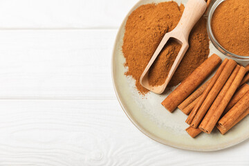 Cinnamon sticks on a textured wooden background. Cinnamon roll. Spicy spice for baking, desserts and drinks. Fragrant ground cinnamon. cinnamon powder Close-up. Place for text. copy space