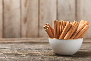 Cinnamon sticks on a textured wooden background. Cinnamon roll. Spicy spice for baking, desserts and drinks. Fragrant ground cinnamon. cinnamon powder Close-up. Place for text. copy space - Powered by Adobe