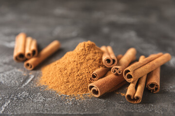 Cinnamon sticks on a textured wooden background. Cinnamon roll. Spicy spice for baking, desserts and drinks. Fragrant ground cinnamon. cinnamon powder Close-up. Place for text. copy space