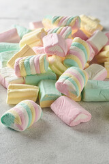 marshmallows close-up, colorful fluffy soft sugar confectionery different shapes and sizes, pile of candy snack pieces on white textured background, selective focus with copy space