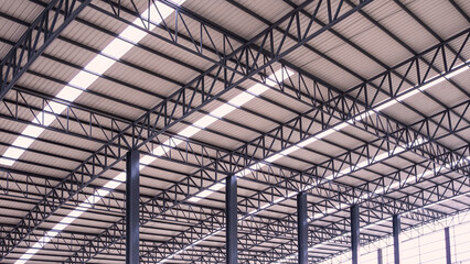 Curve metal roof beam structure with aluminium corrugated steel roof and skylights inside of large industrial warehouse building, low angle and perspective side view