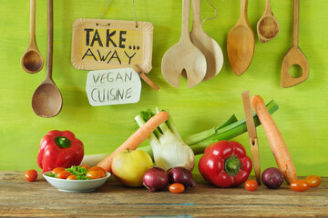 Fresh veggies take away and food delivery service with fresh vegetables,wooden kitchen utensils and promotional sign.Vegetarian lifestyle,eat trend, celebrate healthy food concept