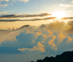 mountain ridge silhouette in dense mist and clouds at the sunset
