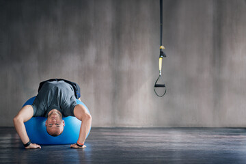 Man, physio ball and stretch for back strength, health or wellness in fitness studio. Sports...