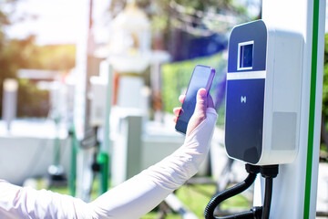 EV Driver use smartphone to scan QR Code on electric vehicle charging stations to pay for electricity.